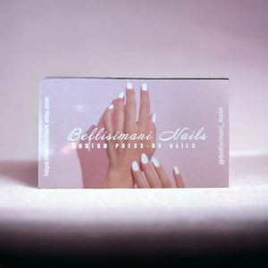 May include: A business card featuring the text "Bellisimani Nails" and "Custom Press-On Nails" with a hand model wearing white press-on nails. The card has a light pink background and the Etsy shop URL is visible.