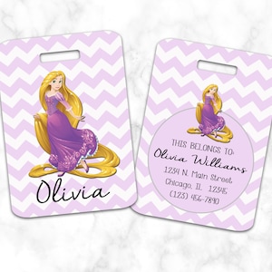 May include: Purple and white chevron patterned luggage tag with a cartoon image of a princess with long blonde hair. The tag has a clear circle with the text "THIS BELONGS TO Olivia Williams 1234 N. Main Street Chicago, IL 12345 (123) 456-7890". The tag also has the name "Olivia" printed below the image.