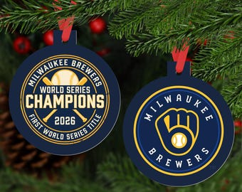 May include: Two circular navy blue ornaments with red ribbons. The left ornament features a baseball, crossed bats, and text reading Milwaukee Brewers World Series Champions 2026 First World Series Title. The right ornament displays the Milwaukee Brewers logo.
