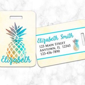 May include: A luggage tag with a watercolor pineapple design. The tag is beige with a blue border and the name "Elizabeth" is printed in blue. The back of the tag has a blue border and the text "Elizabeth Smith, 123 Main Street, Anytown, IL 12345, 123-456-7890".