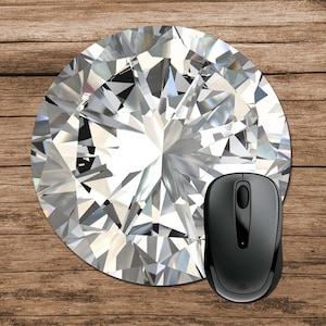 Könnte beinhalten: Eine runde Mauspad mit einem großen, funkelnden Diamantenmuster. Eine schwarze kabellose Computermaus liegt auf dem Mauspad.