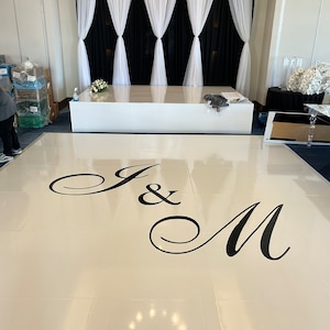 May include: A white dance floor with a black "J & M" monogram in a cursive font.