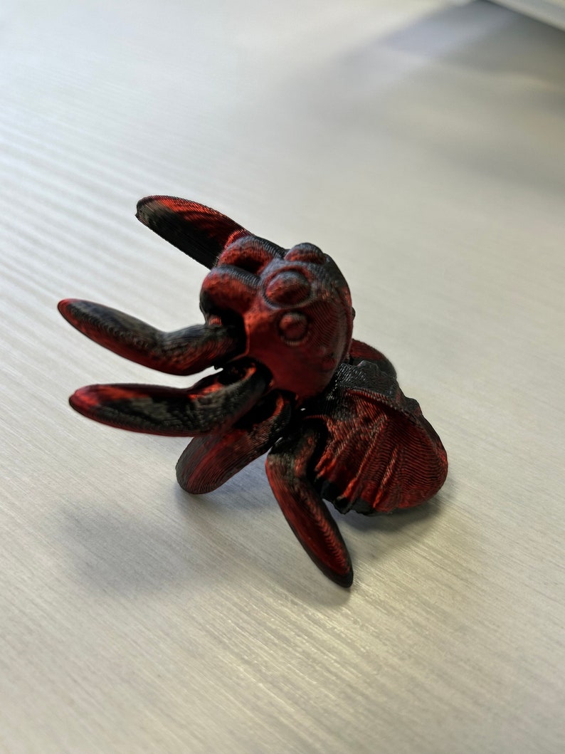 May include: A 3D printed red and black spider figurine with a detailed design.