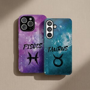 May include: Two rectangular phone cases featuring galaxy-themed backgrounds. The left case is purple with the text PISCES and the Pisces symbol. The right case is teal with the text TAURUS and the Taurus symbol. Both cases have camera cutouts.