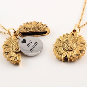 May include: Gold necklace with a sunflower locket that opens to reveal a silver disc with the text "I love my mom" engraved on it.