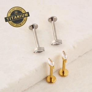 May include: Three pairs of surgical steel body jewelry with marquise-shaped clear gems. Two pairs are silver and one pair is gold.