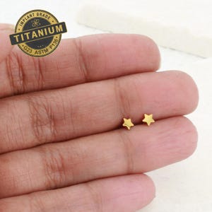 May include: A pair of gold star stud earrings. The earrings are small and delicate, and they are perfect for everyday wear.