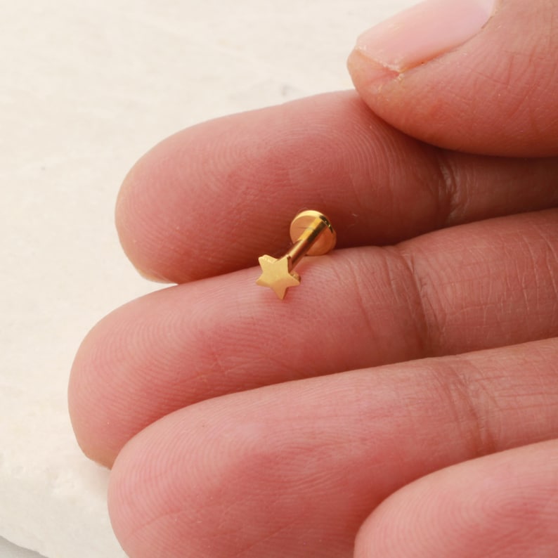 May include: Gold star shaped stud earring for a nose or ear piercing.
