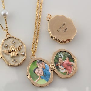 May include: Gold locket necklace with a white enamel angel design and a photo locket with a family photo inside. The back of the locket has the inscription "Love you Dad".