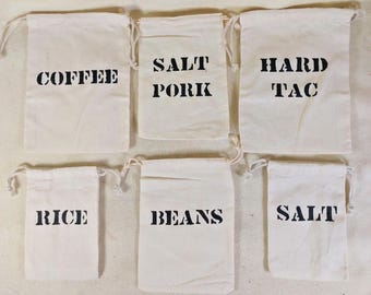 May include: Six off-white canvas drawstring bags, each labeled in bold black letters. The bags are labeled: "COFFEE", "SALT PORK", "HARD TAC", "RICE", "BEANS", and "SALT". The bags are arranged in two rows of three.
