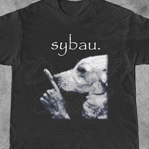 May include: Black t-shirt featuring a dog with a finger to its lips, with the word "sybau." above the dog. The dog is in a black and white graphic design. The shirt is a crew neck.