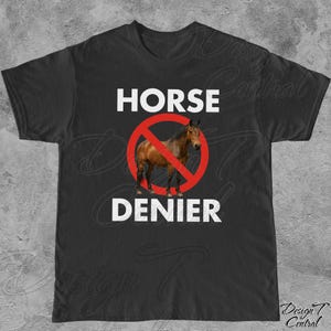 Peut inclure: T-shirt noir avec l'inscription blanche "HORSE DENIER". Un cheval brun est &agrave; l'int&eacute;rieur d'un cercle rouge barr&eacute; d'une ligne rouge. Le t-shirt a un col rond.