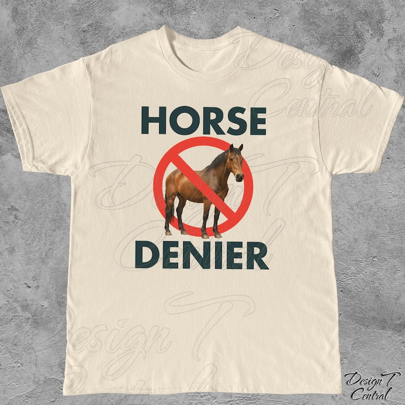 Peut inclure: T-shirt cr&egrave;me avec l'inscription "HORSE DENIER" en bleu fonc&eacute;. Un cheval brun est repr&eacute;sent&eacute; &agrave; l'int&eacute;rieur d'un cercle rouge barr&eacute;. Le t-shirt a un col rond et des manches courtes.