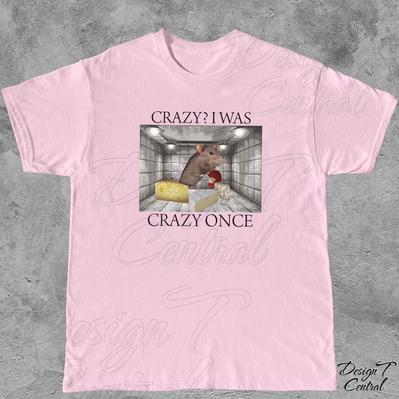 Puede incluir: Camiseta rosa claro con un gr&aacute;fico que presenta una rata de dibujos animados en una habitaci&oacute;n con queso. El texto de la camiseta dice "CRAZY? I WAS CRAZY ONCE". La camiseta es de cuello redondo.