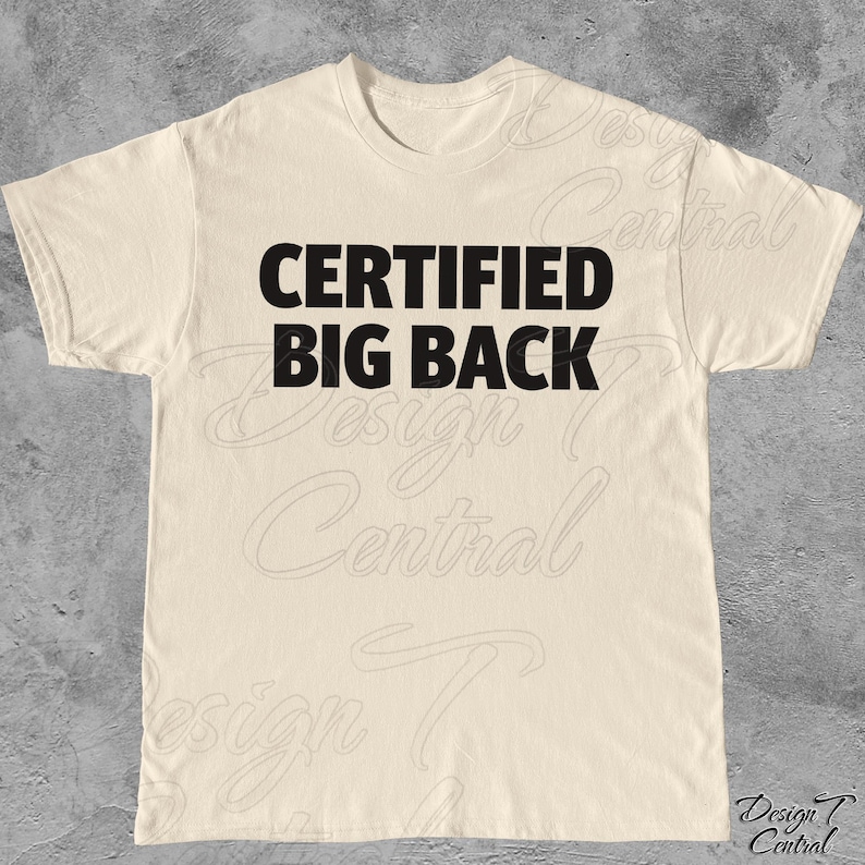 May include: A cream-coloured t-shirt featuring the text "CERTIFIED BIG BACK" in bold, black lettering. The shirt has a crew neck and short sleeves. The design is centrally placed on the front of the garment.