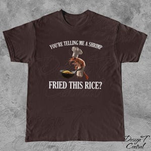 May include: A brown t-shirt with the text "You're telling me a shrimp fried this rice?" and a cartoon shrimp wearing a chef's hat holding a pan of fried rice.