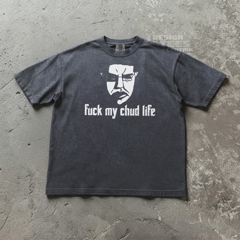 May include: Dark gray t-shirt with a white graphic of a face and the text "fuck my chud life". The shirt has short sleeves and a crew neck. The graphic is centered on the front of the shirt.