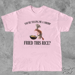 May include: Pink t-shirt with a graphic of a shrimp wearing a chef's hat and holding a wok with fried rice. The text "You're telling me a shrimp fried this rice?" is printed on the shirt.