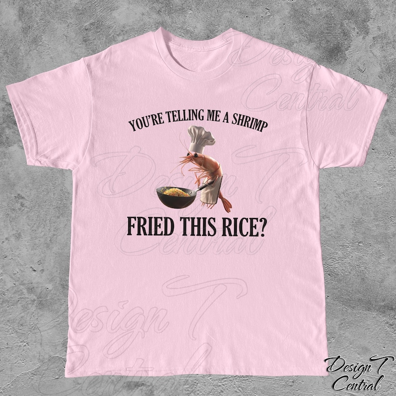 May include: Pink t-shirt with a graphic of a shrimp wearing a chef's hat and holding a wok with fried rice. The text "You're telling me a shrimp fried this rice?" is printed on the shirt.