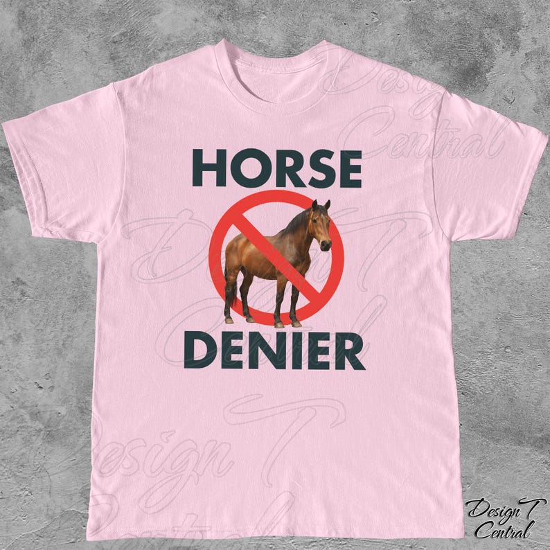 Peut inclure: T-shirt rose clair avec l'inscription "HORSE DENIER" en vert fonc&eacute;. Un cheval brun est &agrave; l'int&eacute;rieur d'un cercle rouge barr&eacute; d'une ligne rouge. Le t-shirt est &agrave; col rond.