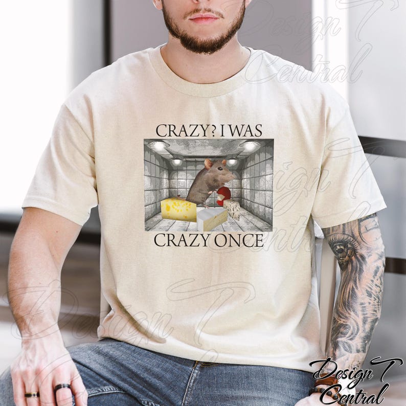 Puede incluir: Camiseta beige con un dise&ntilde;o gr&aacute;fico de una rata en una jaula, queso y el texto "CRAZY? I WAS CRAZY ONCE". La rata lleva guantes de boxeo. La camiseta tiene un dise&ntilde;o casual y humor&iacute;stico.