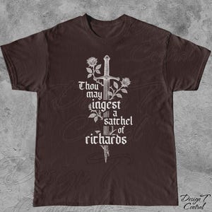 以下が含まれることがあります： 茶色のTシャツ。白いグラフィックデザインで、剣、バラ、そして「Thou may ingest a satchel of richards」というテキストがゴシック体で描かれています。Tシャツは半袖で、クルーネックです。