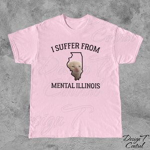 May include: Pink t-shirt with a black outline of the state of Illinois and a cat's face inside. The text "I suffer from mental Illinois" is printed on the shirt.