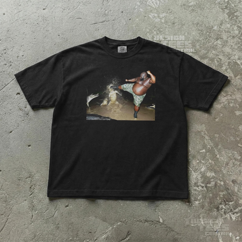 May include: Black t-shirt featuring a humorous image of a person kicking in water. The person is wearing camouflage shorts. The shirt has the text "DESIGN TEES CENTRAL" printed on the top right corner.