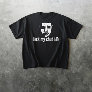 May include: Black t-shirt with a white graphic of a face and the text "fuck my chud life". The shirt is made of a soft material and has short sleeves and a crew neck.