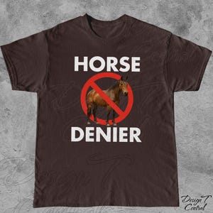 Peut inclure: T-shirt marron avec l'inscription blanche "HORSE DENIER". Un cheval marron est &agrave; l'int&eacute;rieur d'un cercle rouge barr&eacute;. Le t-shirt a un col rond et des manches courtes.