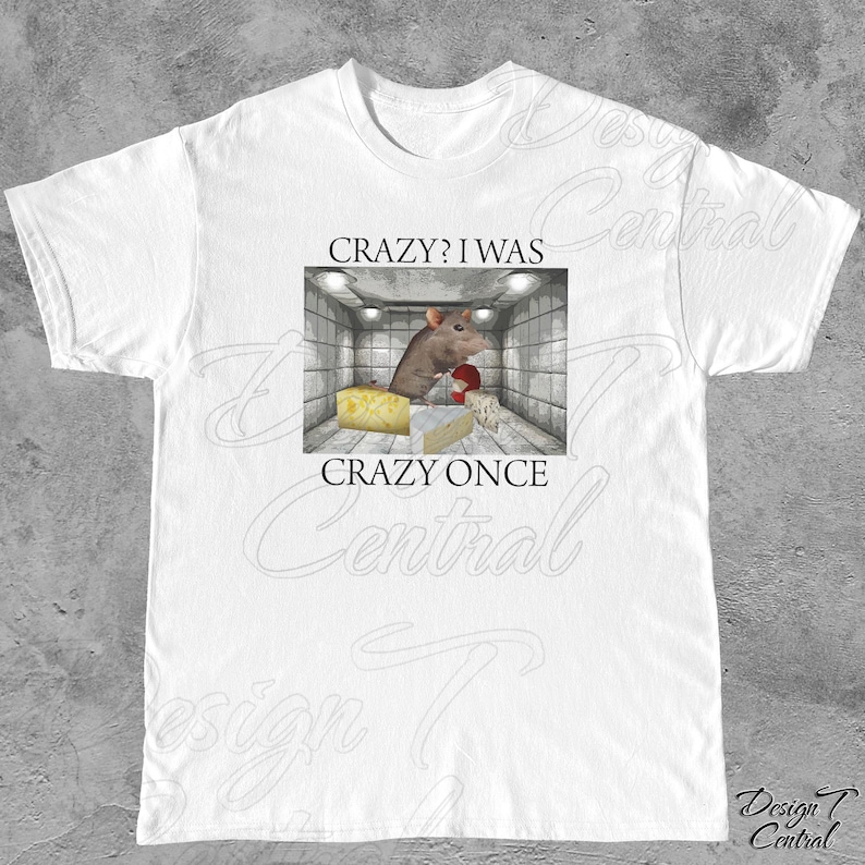 Puede incluir: Camiseta blanca con un gr&aacute;fico que presenta una rata de dibujos animados en un entorno de instituci&oacute;n mental, con queso y el texto "CRAZY? I WAS CRAZY ONCE". El dise&ntilde;o est&aacute; centrado en la camiseta.