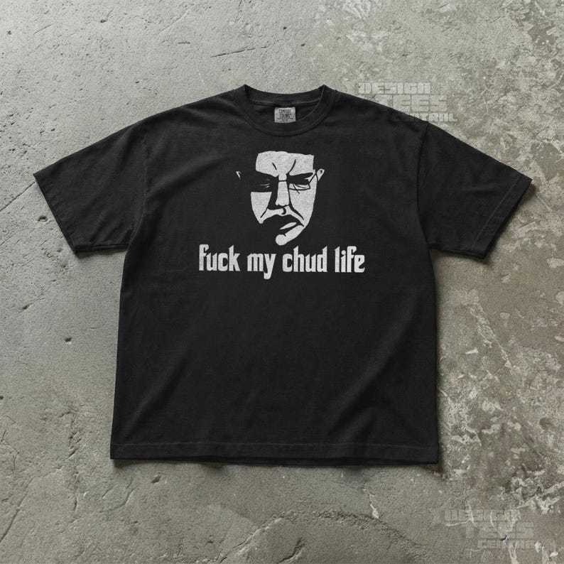 May include: Black t-shirt with a white graphic of a stern face wearing glasses and the text "fuck my chud life". The shirt is a short-sleeved crew neck.