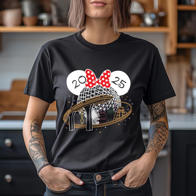 Pu&ograve; includere: Maglietta nera con una grafica di un Spaceship Earth dorato con un fiocco di Minnie Mouse rosso e bianco in cima. Il testo "20 25" &egrave; su entrambi i lati del fiocco.