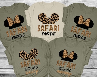 Könnte beinhalten: Fünf grüne und beige T-Shirts mit einem schwarzen und braunen Leoparden-Mickey-Mouse-Design. Die Shirts sagen "Safari Mode" und "Safari Squad" mit den Worten "Daddy" und "Mommy" auf zwei der Shirts.