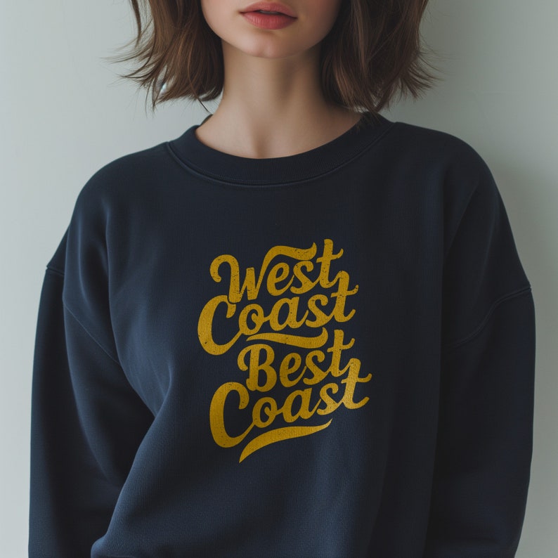 May include: A navy blue sweatshirt with a gold graphic that says "West Coast Best Coast" in a retro font.