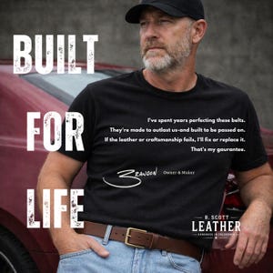 May include: A black t-shirt featuring the white text BUILT FOR LIFE and a quote about leather belts. The shirt includes the signature Brandon Owner & Maker and the B. Scott Leather Handmade in California logo. The wearer has a brown leather belt.