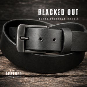 May include: A black leather belt featuring a matte charcoal buckle. The text BLACKED OUT MATTE CHARCOAL BUCKLE is visible at the top, and B. SCOTT LEATHER HANDMADE IN CALIFORNIA is printed at the bottom of the image.