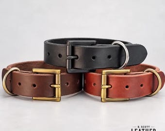 May include: Three leather collars in black, dark brown, and reddish-brown. Each collar features a metal buckle and a D-ring. The black collar has a black buckle, while the brown collars have brass-toned buckles. Text reads B. SCOTT LEATHER.