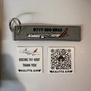 May include: A gray fabric keychain tag with a silver ring, featuring an embroidered image of an airplane and the text "B777-300-ERSF." Two white cards display a Boeing 747-400F image, the text "THANK YOU!" and a QR code, all with the "KALITTA AIR" logo.