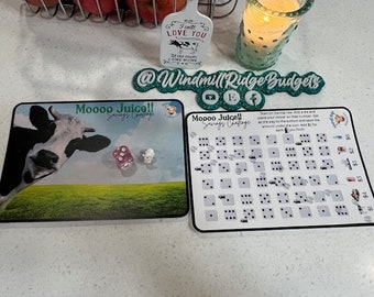 Puede incluir: Un tablero de juego de desafío de ahorro con una ilustración de vaca y el texto "Moooo Juice!! Savings Challenge". El tablero tiene una cuadrícula de cuadrados con números y un dado.