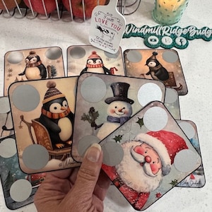 May include: A set of nine Christmas-themed coasters with a silver circle in the centre of each. The coasters feature images of penguins, a snowman, and Santa Claus. The coasters are made of a thick, durable material and are perfect for protecting your furniture from scratches and spills.