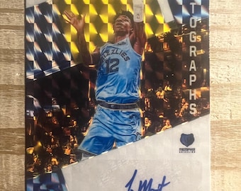 Könnte beinhalten: Eine Basketball-Sammelkarte mit Ja Morant von den Memphis Grizzlies. Die Karte hat einen holografischen Hintergrund mit einem karierten Muster. Die Karte ist von Ja Morant signiert und enthält den Text "AUTOGRAPHS".