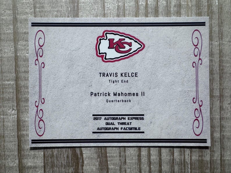 May include: A white card with a red Kansas City Chiefs logo. The card has the text "TRAVIS KELCE Tight End" and "Patrick Mahomes II Quarterback" and "2017 AUTOGRAPH EXPRESS DUAL THREAT AUTOGRAPH FACSIMILE".