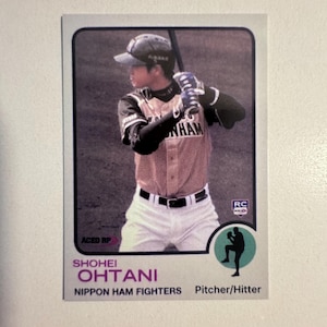 May include: Baseball card featuring Shohei Ohtani of the Nippon Ham Fighters. The card shows Ohtani in a baseball uniform, holding a bat. The card has a retro design with text that includes "Shohei Ohtani" and "Pitcher/Hitter".