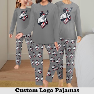May include: A set of grey pyjamas with a custom logo featuring a baseball player. The pyjamas have long sleeves and trousers with a repeating pattern of the logo.