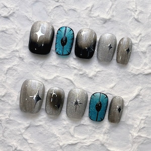 May include: Ten silver and blue nail polish designs. The designs include stars, a blue eye, and a silver eye.