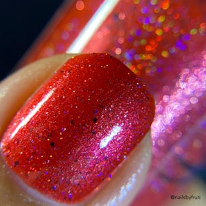 May include: Close-up of a red nail polish with a fine glitter finish. The polish has a subtle shimmer and a high-gloss finish.