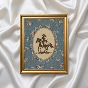 May include: A framed print featuring a sepia-toned illustration of a person riding a horse. The image is set within an oval frame against a blue floral background, surrounded by a gold-colored frame.