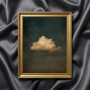 Puede incluir: Una impresión artística enmarcada que presenta una nube sobre un fondo azul verdoso y marrón oscuro. La nube es de color beige claro. El marco es dorado y rectangular.