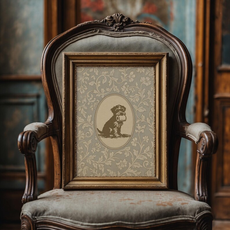 Puede incluir: Un grabado enmarcado con un perro marr&oacute;n sosteniendo un rollo de papel, sobre un fondo floral beige. El grabado est&aacute; en un marco dorado y descansa sobre una silla vintage tapizada con marco de madera.